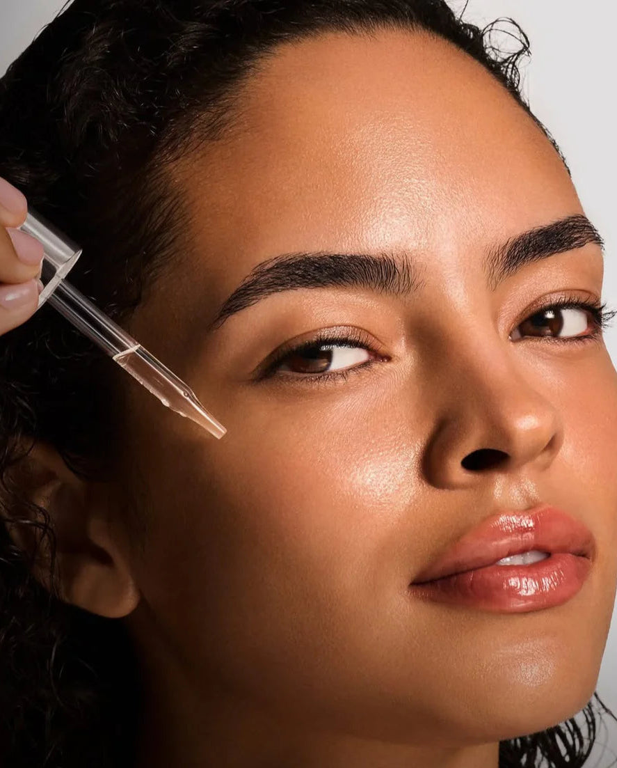 Woman applying a dropper of skincare product to her face with text on how to use it.